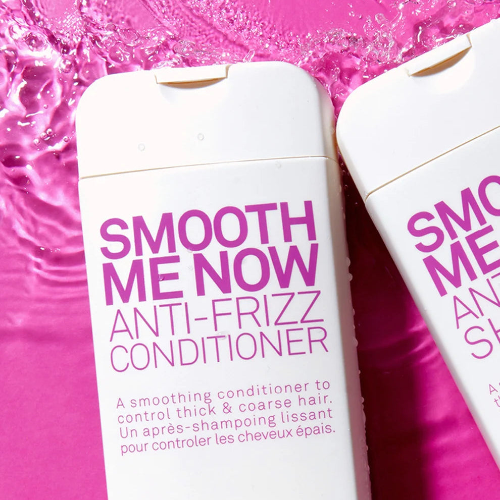 Two bottles of Eleven Smooth Me Now Anti-Frizz Conditioner' on a pink background with water droplets.