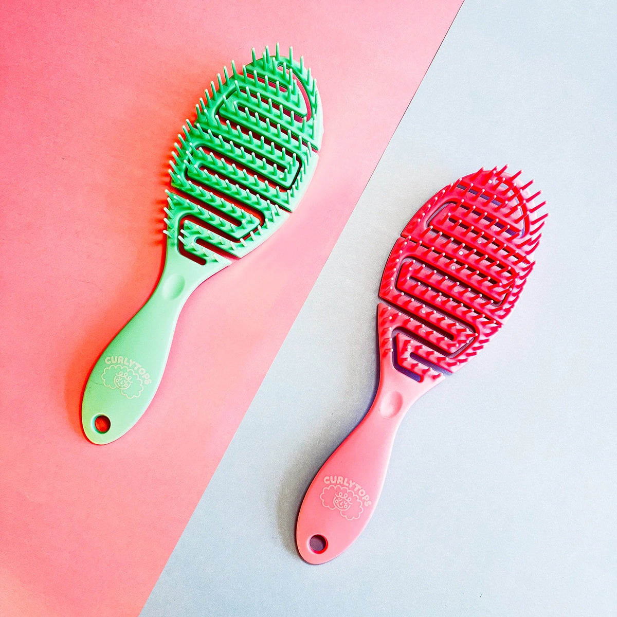Green and pink hairbrushes on a pink and gray gradient background