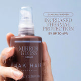 A hand holding a brown Mirror Gloss Serum bottle with water droplets dripping from the fingers, set against a light blue background with promotional text.